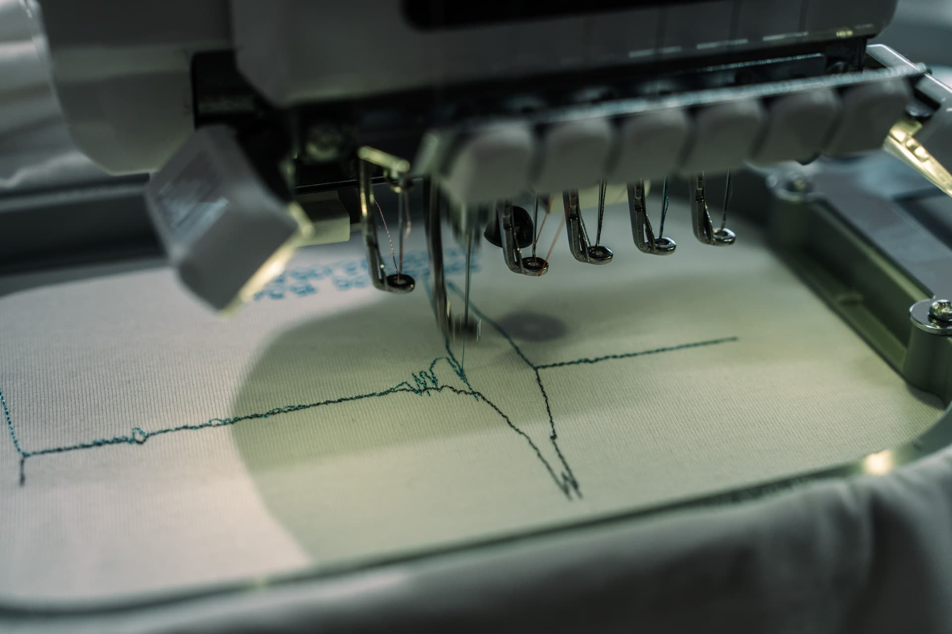 刺繍機が白い生地に波形を縫っている